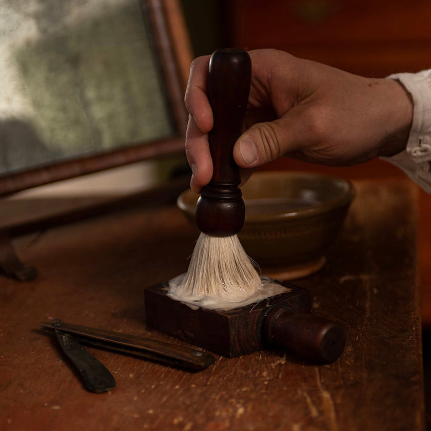 18th Century brush being lathered in a soap block to achieve an optimal shave for Colonial America