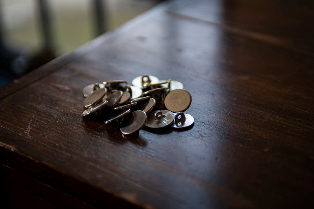 A group of 18th Century accurate 7/8 inch Pewter Buttons are set on a counter top.